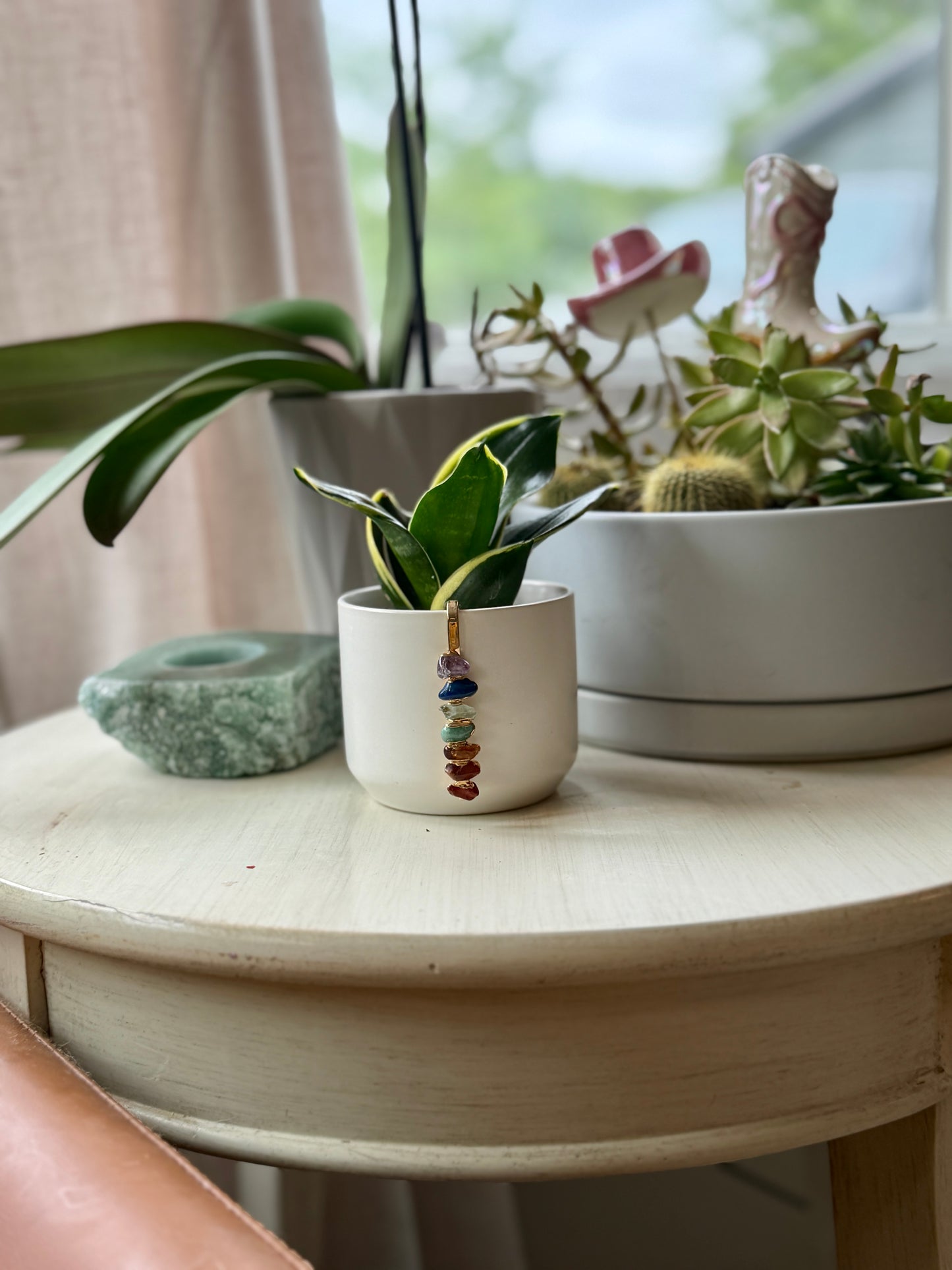 White Ceramic Pot with Aligned Chakra Pendant and Snake Plant